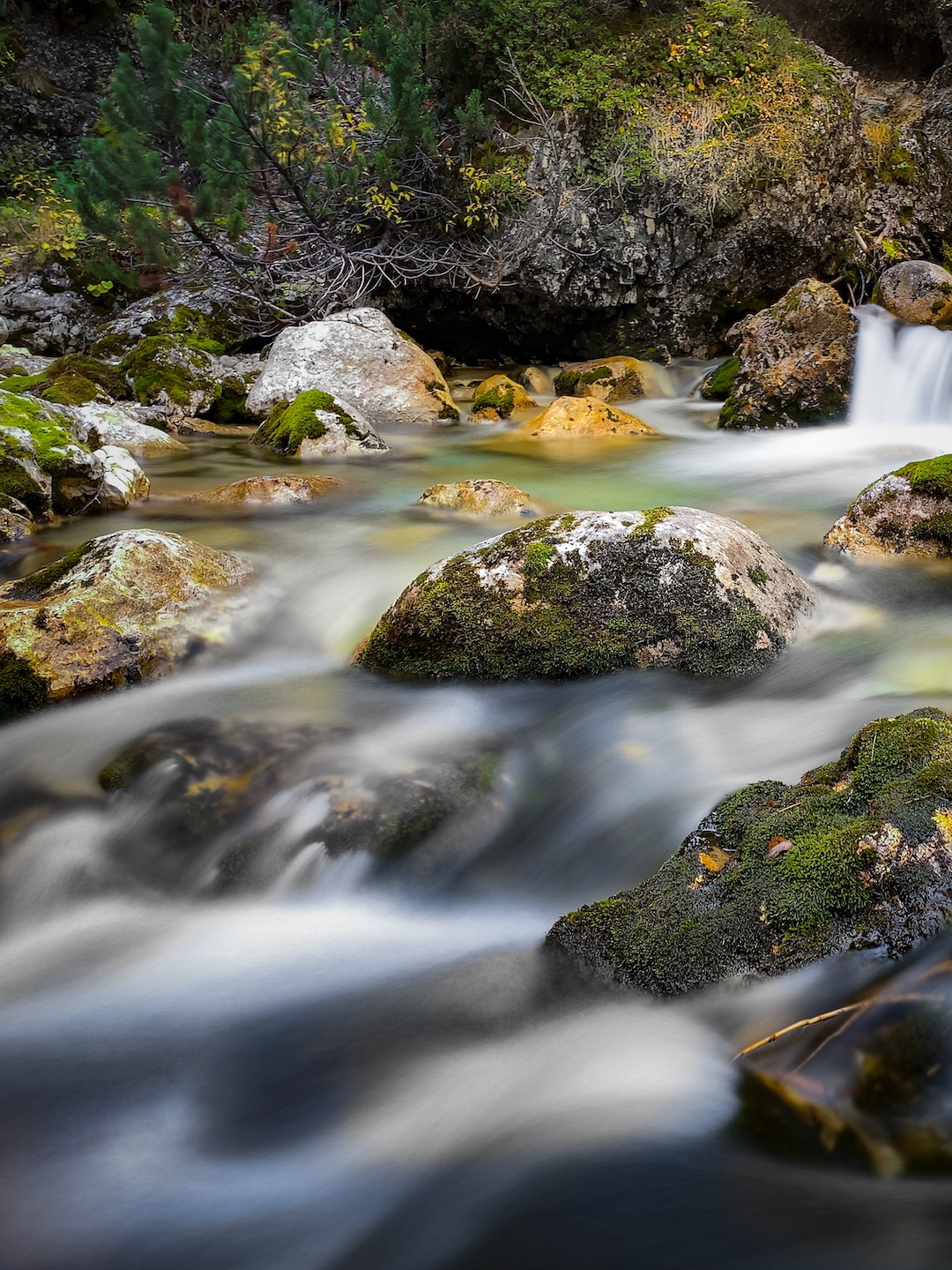 A stream photographed on iPhone, with the moving water blurred into a smooth, silky long exposure.