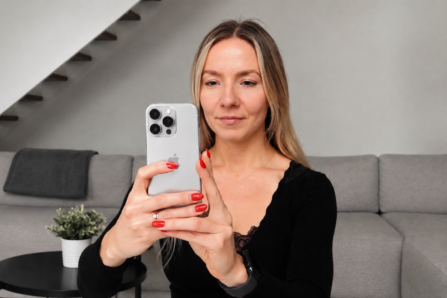 Laine sitting on a sofa, taking a photo with her iPhone.
