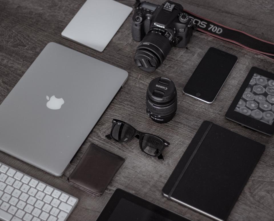 A mirrorless camera and a smartphone placed side by side on a wooden table.